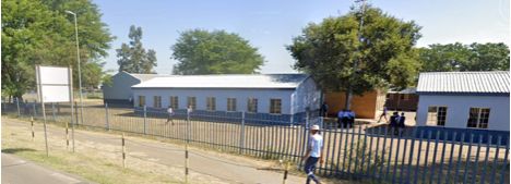 Single-storey school buildings behind a fence at the Elandsdrift pilot site